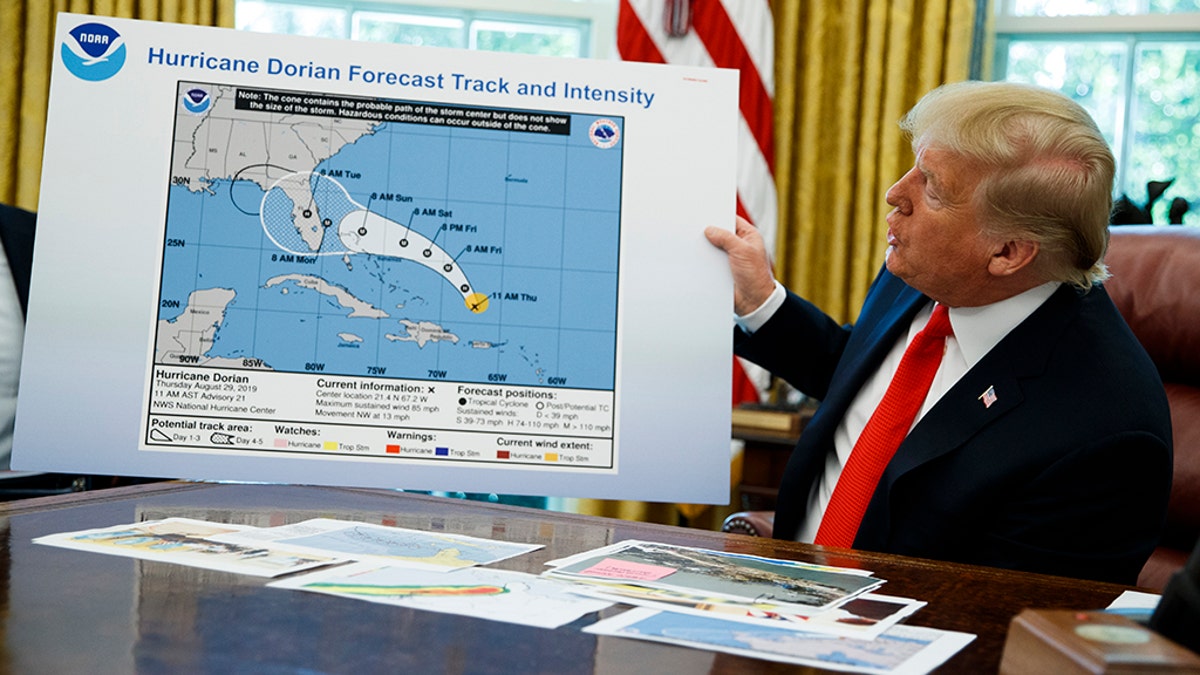 President Donald Trump holds a chart as he talks with reporters after receiving a briefing on Hurricane Dorian in the Oval Office of the White House, Wednesday, Sept. 4, 2019, in Washington. (AP Photo/Evan Vucci)