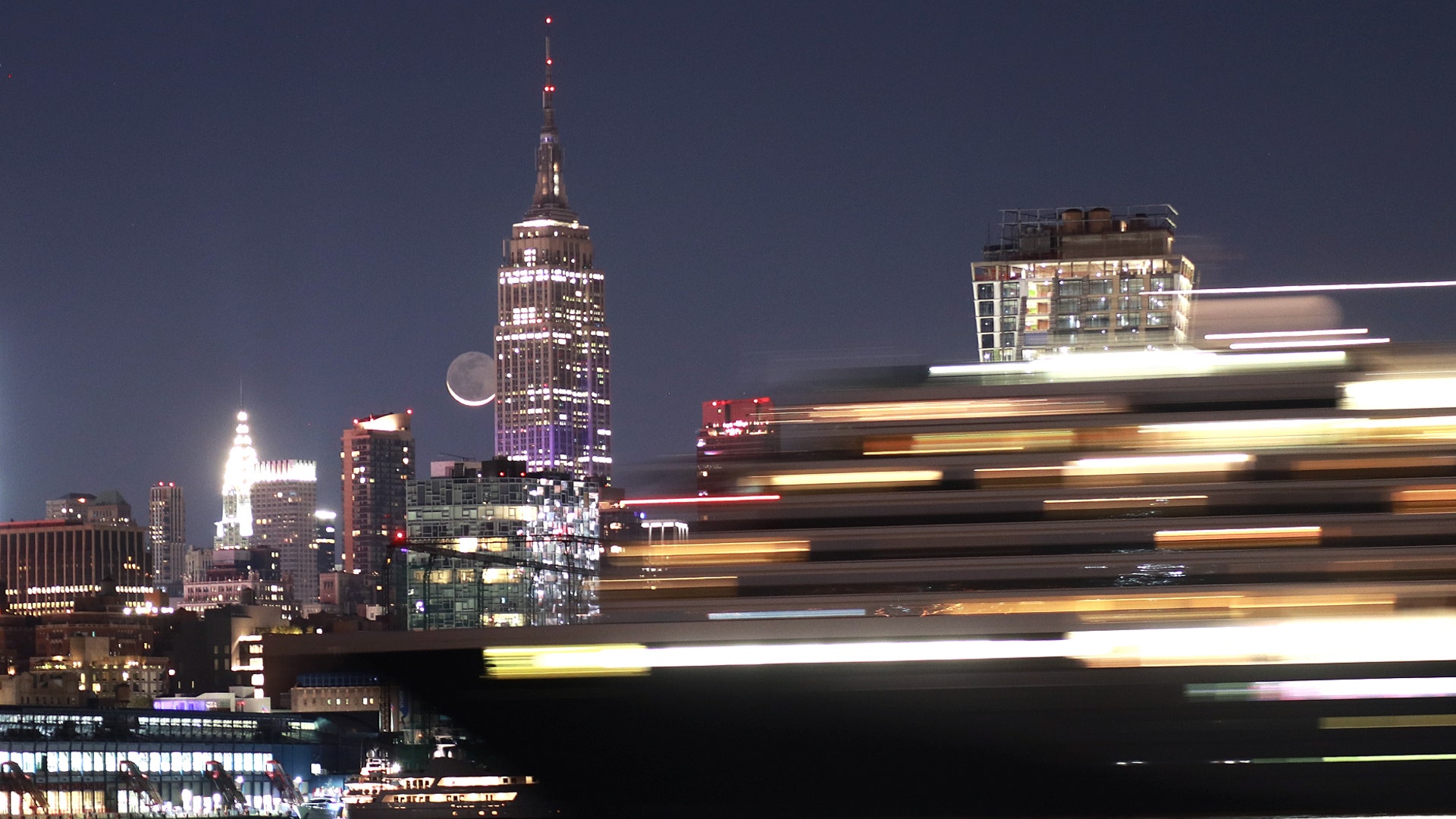 The moon rises behind the Empire State Building as a cruise ship returns to port before sunrise in New York City, Sept. 27, 2019