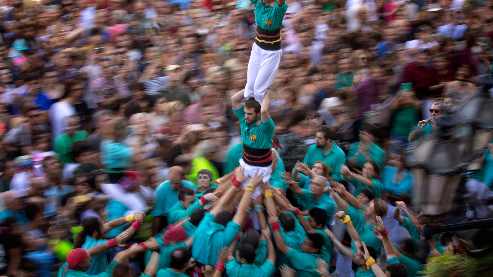Participants walk maintaining a human tower or "Castellers" during the Saint Merce celebrations in San Jaume square in Barcelona, Spain, Sept. 24, 2019.