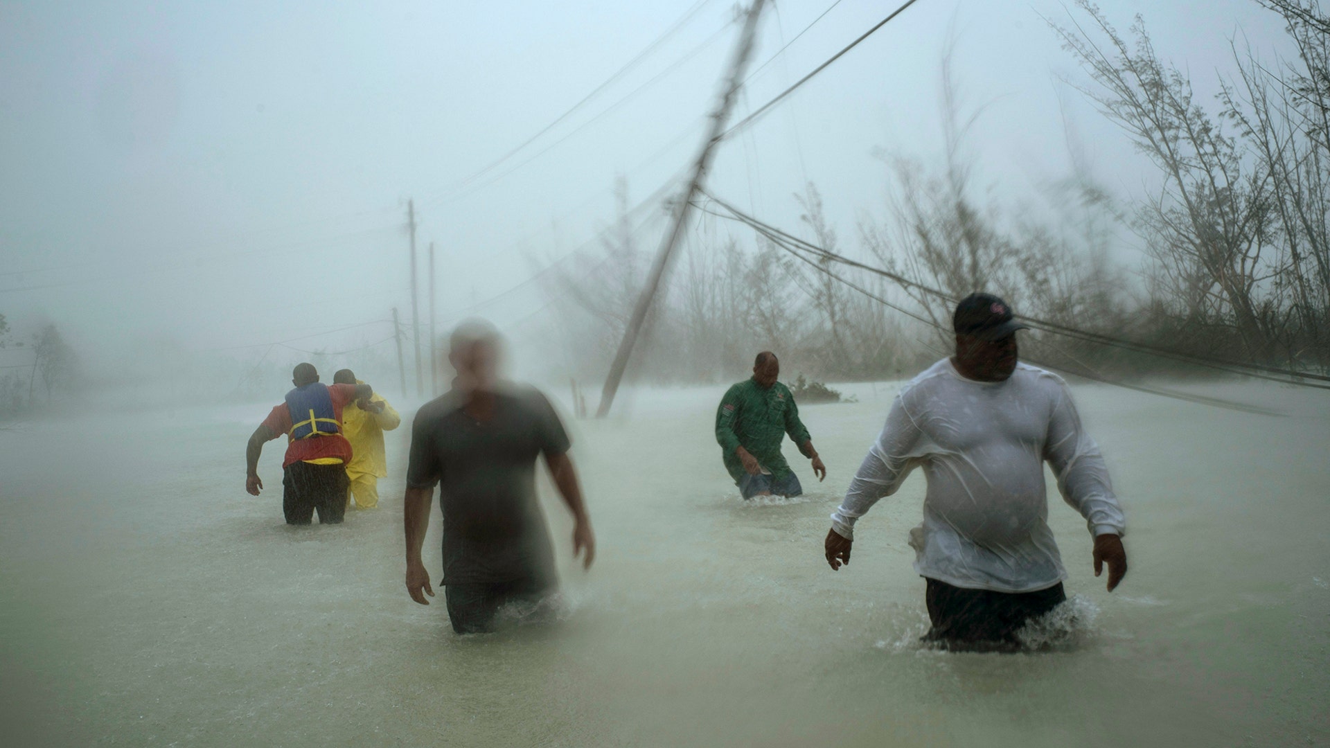 Volunteers walk under the wind and rain from Hurricane Dorian through a flooded road as they work to rescue families near the Causarina Bridge in Freeport, Grand Bahama, Bahamas, Sept. 3, 2019. 