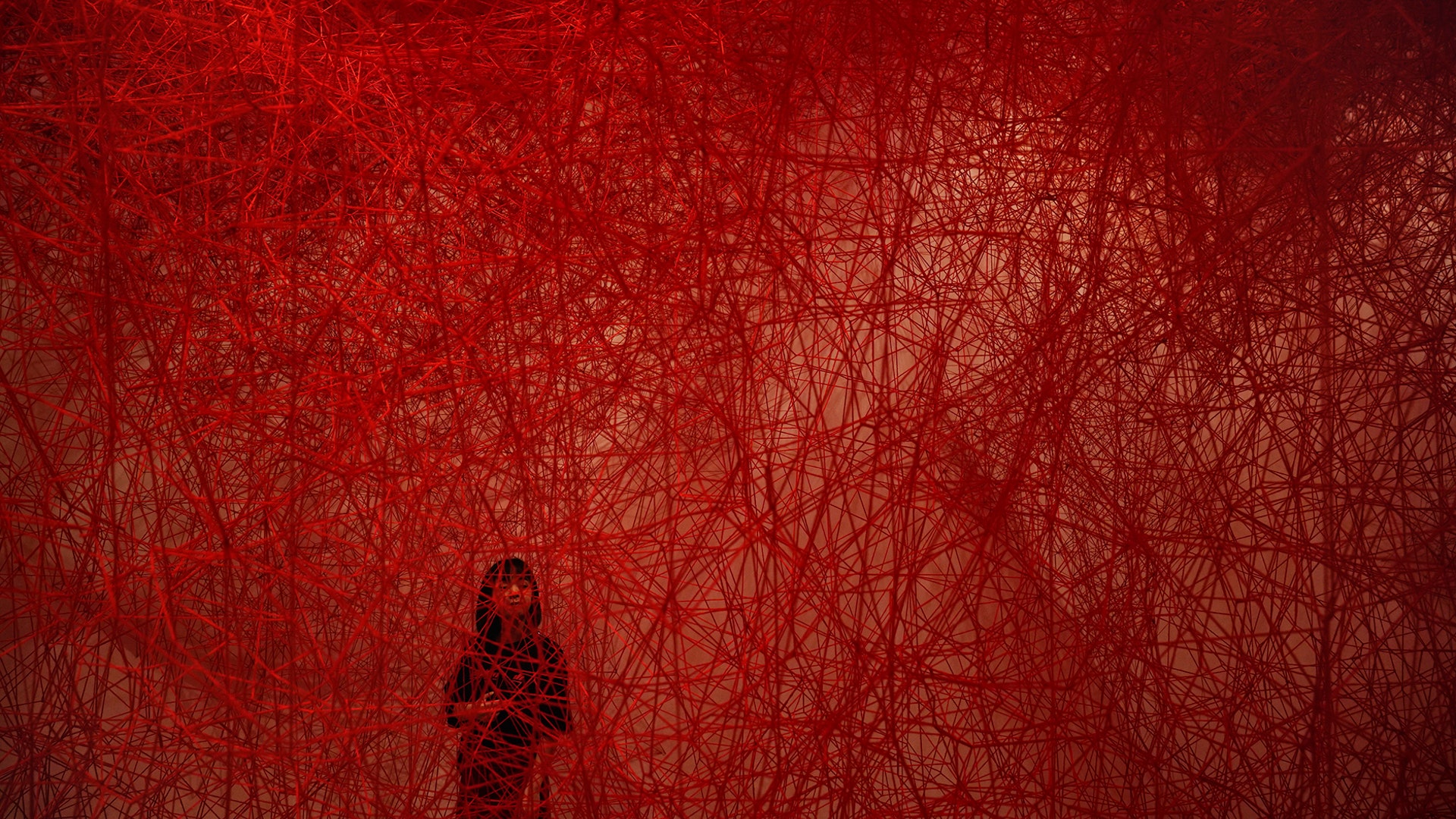 A woman looks at Chiharu Shiota's art installation titled "Uncertain Journey" at the Mori Art Museum, in Tokyo, Sept. 19, 2019.