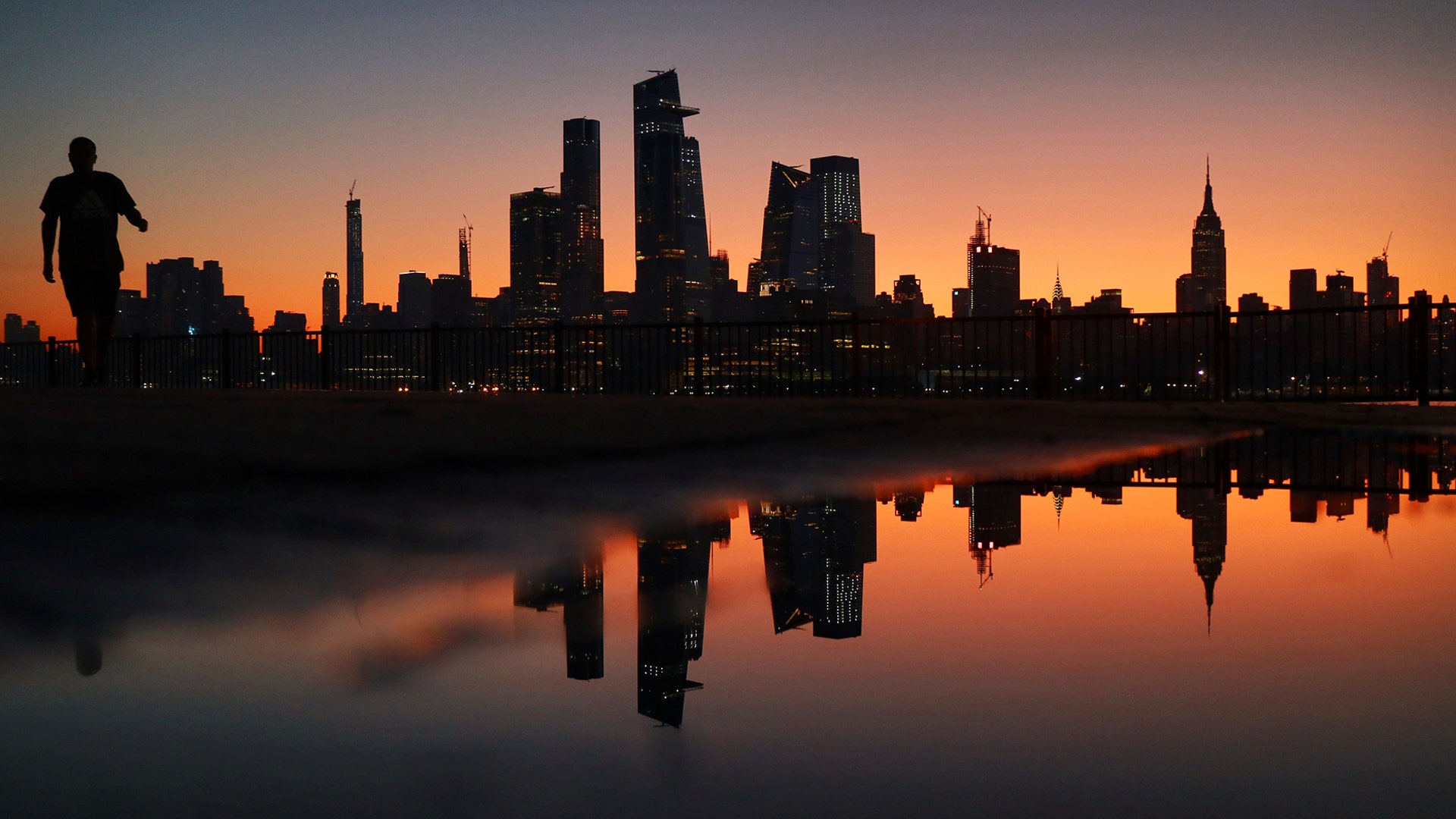A man walks in front of the skyline of midtown Manhattan as the sun rises in New York City, Sept. 22, 2019.