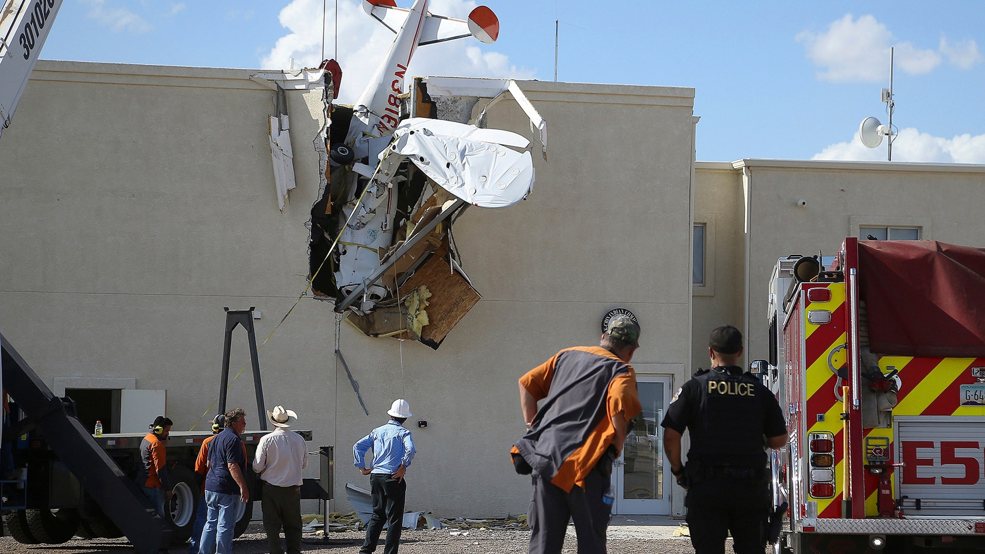 Police and fire personnel look on as workers remove a single-engine plane after it crashed into the terminal building shortly after takeoff at the Ak-Chin Regional Airport in Maricopa, Arizona, Sept. 10, 2019.