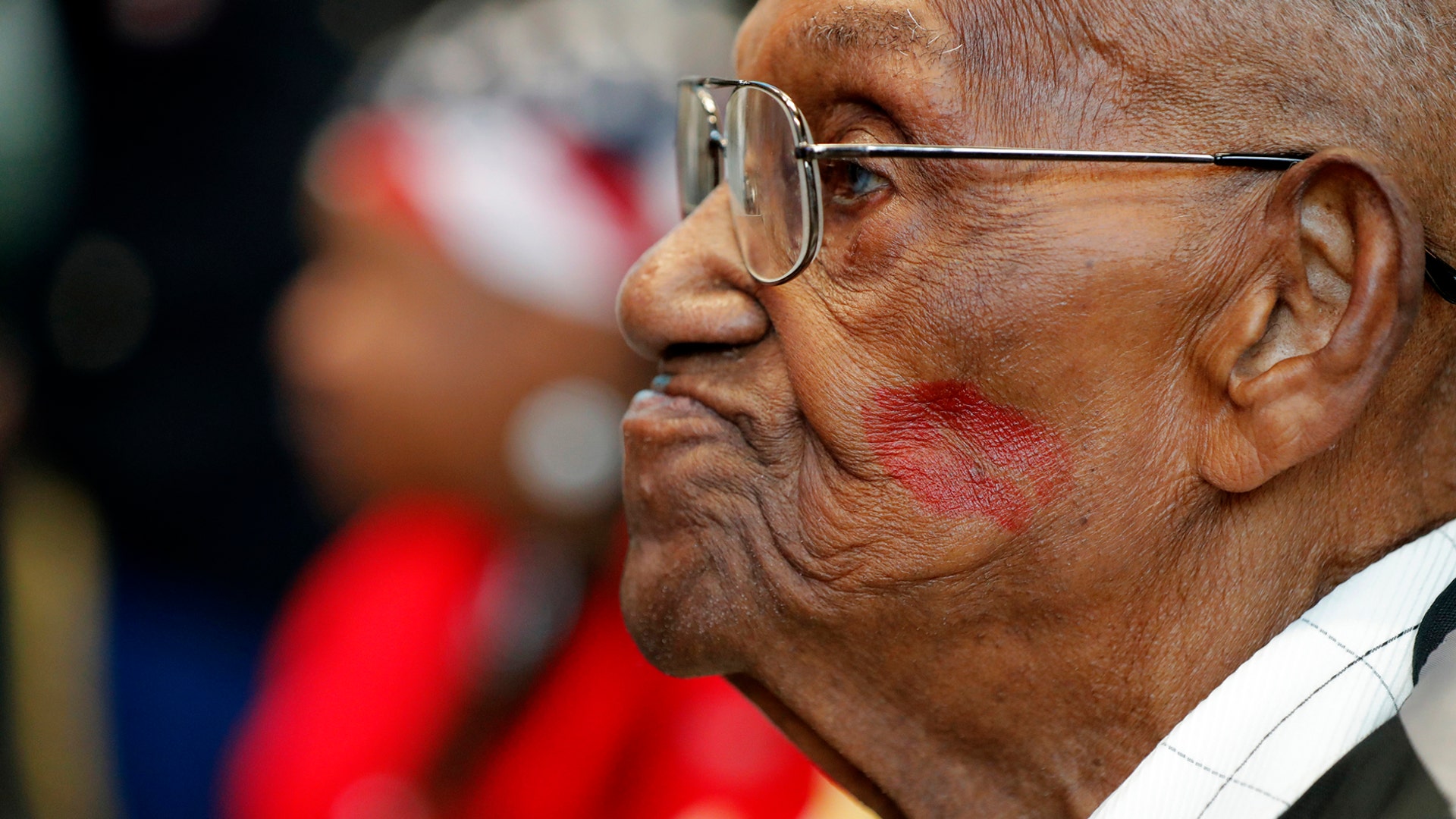 World War II veteran Lawrence Brooks sports a lipstick kiss on his cheek, planted by a member of the singing group Victory Belles, as he celebrates his 110th birthday at the National World War II Museum in New Orleans, Sept. 12, 2019. 