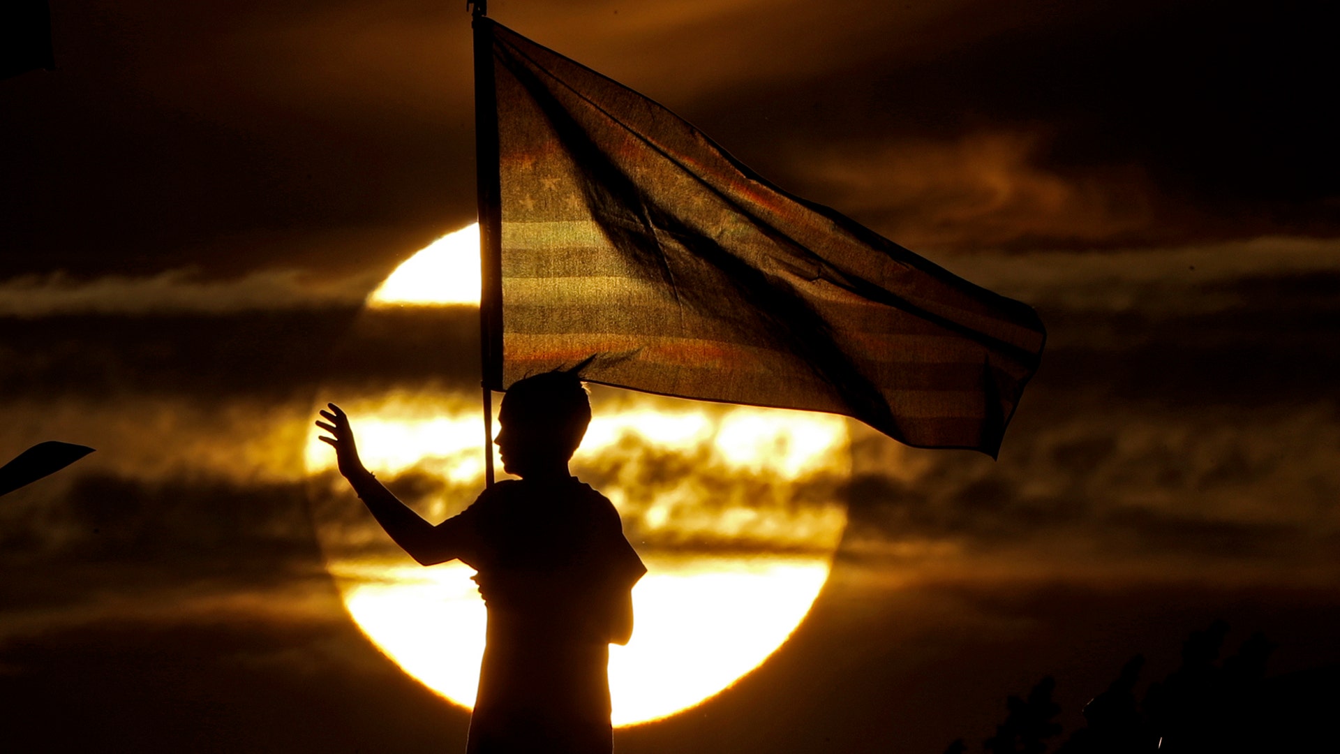 A boy waves to passing motorists to commemorate the anniversary of the Sept. 11 terrorist attacks from an overpass on Interstate 35 in Melvern, Kansas, Sept. 11, 2019.
