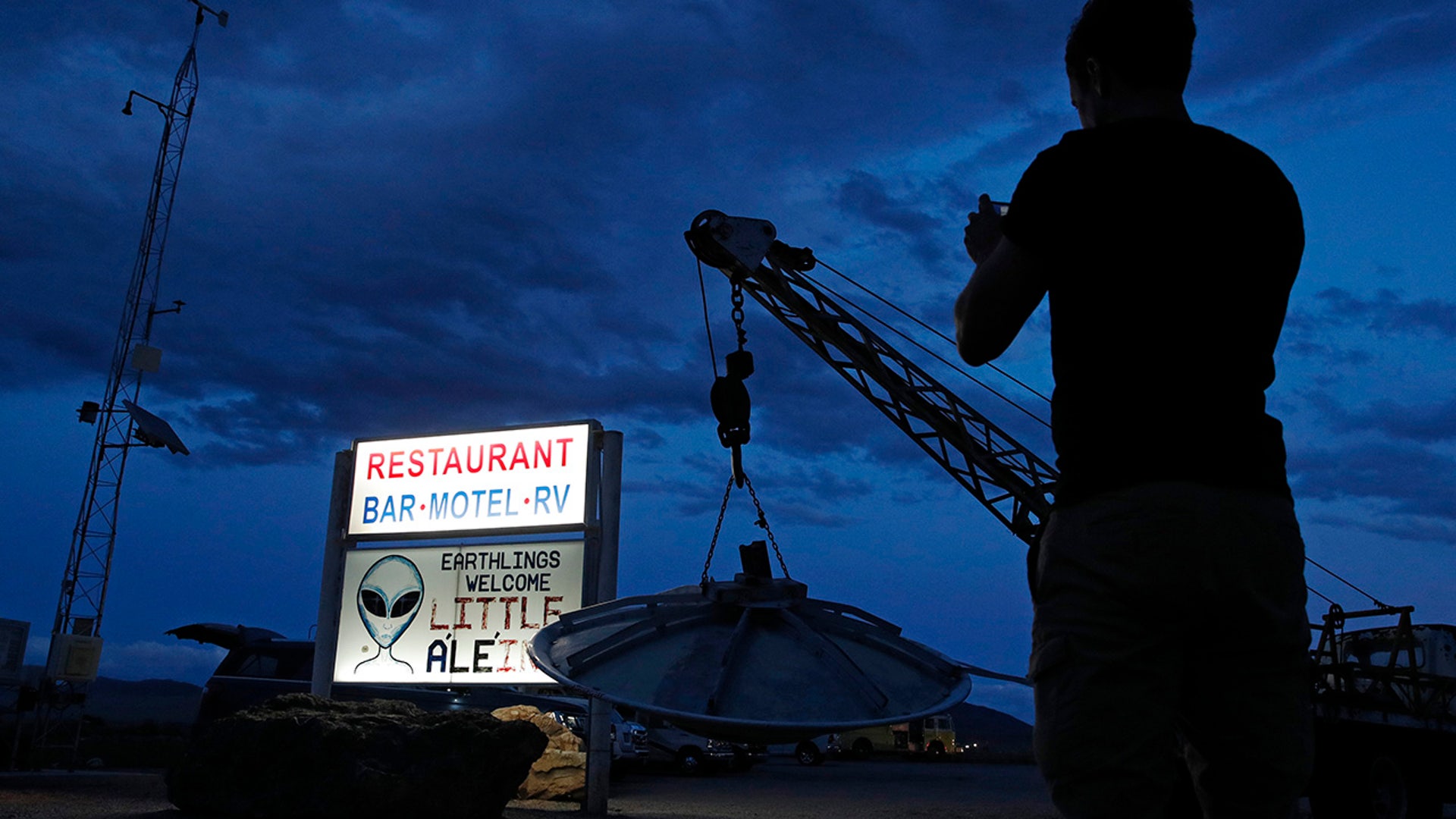 A man takes a picture of a sign at the Little A'Le'Inn during an event inspired by the "Storm Area 51" internet hoax, Thursday, Sept. 19, 2019, in Rachel, Nev. Hundreds have arrived in the desert after a Facebook post inviting people to "see them aliens" got widespread attention and gave rise to festivals this week. (AP Photo/John Locher)