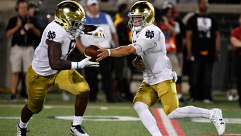 Notre Dame's Ian Book hits Louisville cheerleader in face with football on errant throw