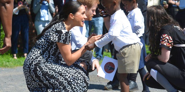 Britain's royal couple Prince Harry and Meghan Duchess of Sussex, greet children on their arrival at the Nyanga Methodist Church in Cape Town, South Africa, Monday, Sept, 23, 2019. It houses a project where children are taught about their rights, self-awareness and safety, and are provided self-defense classes and female empowerment training to young girls in the community. The royal couple are starting their first official tour as a family with their infant son, Archie.