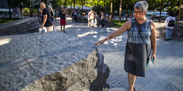 A visitor touches one of the granite slabs at the 9/11 Memorial Glade in New York City. When the names of nearly 3,000 Sept. 11 victims are read aloud today at the World Trade Center, a half-dozen stacks of stone will quietly salute an untold number of people who aren’t on the list. (AP)