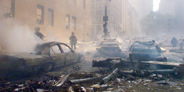 Cars smoulder in the street as the destroyed World Trade Center burns in New York on September 11, 2001. Two hijacked commercial planes slammed into the twin towers of the World Trade Center causing both 110-story landmarks to collapse in thunderous clouds of fire and smoke. REUTERS/Peter Morgan