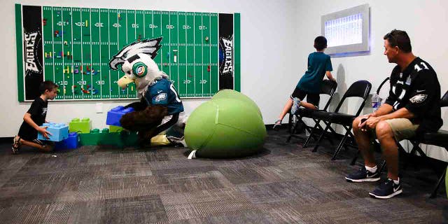 In this Thursday, Aug. 22, 2019, photo, Victor Ykoruk, right, watches as his 10-year-old twin sons, Ryan, left, and Jack, play in the Lincoln Financial Field sensory room, before a preseason NFL football game between the Philadelphia Eagles and the Baltimore Ravens in Philadelphia. (AP Photo/Matt Rourke)