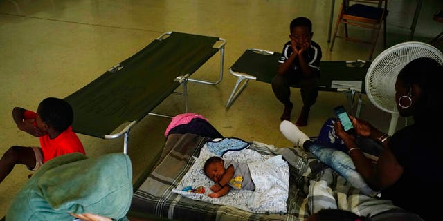 Anastacia Makey, 43, at the far right, looks at her phone while she and her family are sitting on beds with other residents inside a church Open as a shelter while they were waiting for Hurricane Dorian at Freeport, Grand Bahama, Bahamas, Sunday, September 1, 2019. Hurricane Dorian has further intensified on Sunday while it's still going strong. it was getting closer to the north of the Bahamas, threatening to hit islands with force 5 winds, waves and torrential rains. 