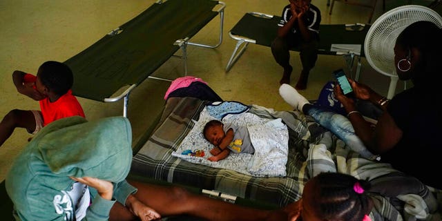 Anastacia Makey, 43, far right, looks at her phone as she and her family sits on cots with other residents inside a church that was opened up as a shelter as they wait out Hurricane Dorian in Freeport on Grand Bahama, Bahamas, Sunday, Sept. 1, 2019. Hurricane Dorian intensified yet again Sunday as it closed in on the northern Bahamas, threatening to batter islands with Category 5-strength winds, pounding waves and torrential rain.