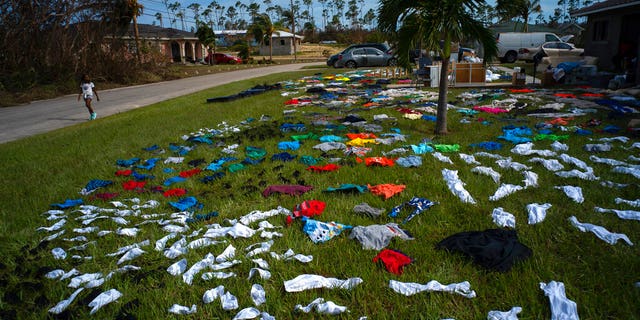 A child walks past clothes laid out to dry on a field in the aftermath of Hurricane Dorian, in the Arden Forest neighborhood of Freeport, Bahamas, Wednesday, Sept. 4, 2019. (Associated Press)