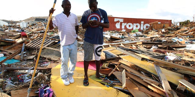 Haitian Burris Filburt, right, and another man stand on the extensive damage and destruction in the aftermath of Hurricane Dorian is seen in The Mudd, Great Abaco, Bahamas, Thursday, Sept. 5, 2019. 