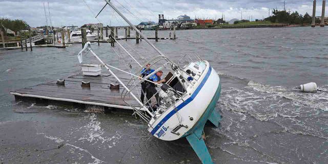 Beaufort Police Officer Curtis Resor, left, and Sgt. Michael Stepehens check a sailboat for occupants in Beaufort, N.C. after Hurricane Dorian passed the North Carolina coast on Friday, Sept. 6, 2019. (AP Photo/Tom Copeland)