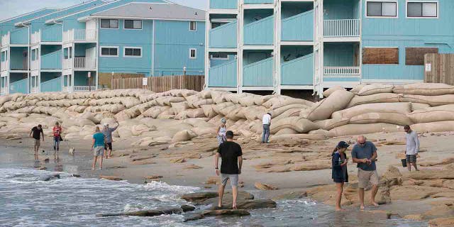 Beachgoers looks for shells in the aftermath of Hurricane Dorian in from of The Riggings beachfront condominiums at Kure Beach, N.C., Friday, Sept. 6, 2019.