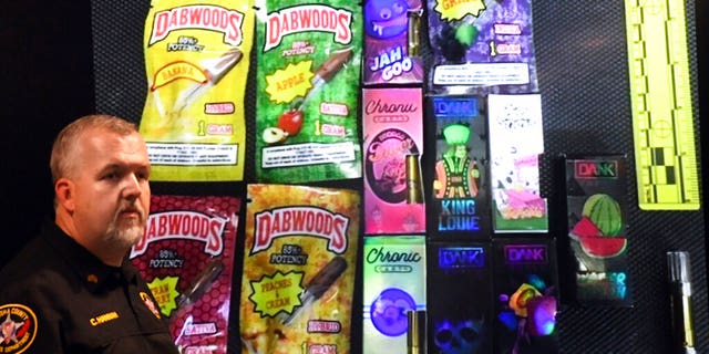 Sgt. Christopher Hannah of the Kenosha County Sheriff's Department stands in front of a display of the colorfully packaged vaping products during a news conference.