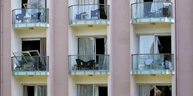 A worker on a balcony, below right, cleans up the debris after an explosion at an army's munitions depot near the coastal city of Kyrenia in the Turkish occupied area at northern Cyprus, Thursday, Sept. 12, 2019.
