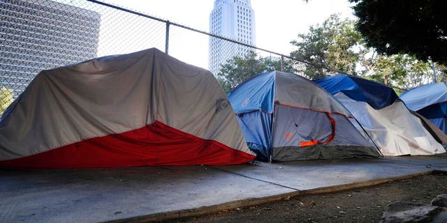 Los Angeles City Hall behind a homeless tent encampment along a street in downtown Los Angeles this past July. (AP Photo/Richard Vogel, File)