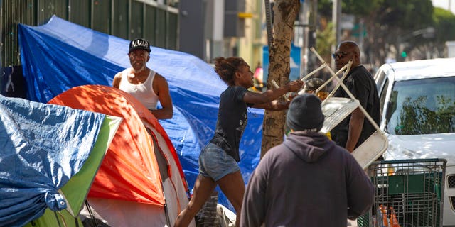 A homeless woman throwing a plastic chair in the air in downtown Los Angeles on Tuesday. Los Angeles Mayor Eric Garcetti said he hoped President Trump will work with the city to end homelessness. (AP Photo/Damian Dovarganes)