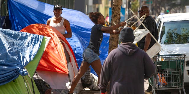 A homeless woman throwing a plastic chair in the air in downtown Los Angeles on Tuesday. Los Angeles Mayor Eric Garcetti said he hoped President Trump will work with the city to end homelessness. (AP Photo/Damian Dovarganes)