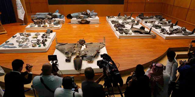 Journalists film what Saudi military spokesman Col. Turki al-Malki said was evidence of Iranian weaponry used in the attack targeted Saudi Aramco's facilities in Abqaiq and Khurais, during a press conference in Riyadh, Saudi Arabia, Wednesday, Sept. 18, 2019. (AP Photo/Amr Nabil)