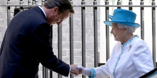 FILE - In this Tuesday, July 24, 2012 file photo, Britain's Queen Elizabeth II is greeted by Britain's Prime Minister David Cameron, as she arrives for lunch at Downing Street in London.