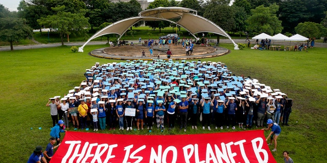 Environmental activists, mostly students, display their message in front of "a human globe" formation to coincide with the global protests on climate change Friday, Sept. 20, 2019, at the University of Philippines campus in suburban Quezon city northeast of Manila, Philippines. Various environmental groups in the country are participating in what is expected to be the world's largest mobilization on climate change known as "Global Climate Strikes."
