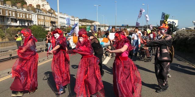 Extinction Rebellion protesters occupy one side of a dual carriageway at the port of Dover, England, Saturday Sept. 21, 2019. Traffic around the Port of Dover, England's major sea connection with France, has been disrupted as a result of a protest by environmental activists. Activists from Extinction Rebellion said their protest around the port is intended to "highlight the vulnerability of the U.K.'s food supply in the face of the ecological and climate emergency." (Michael Drummond/PA via AP)