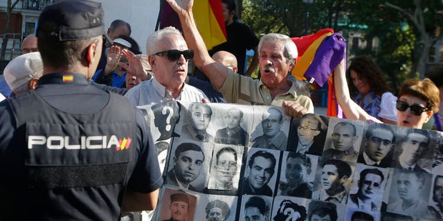 Protesters shout behind a banner showing photos of Spanish Civil War victims, outside the Supreme Court in Madrid, Spain, Tuesday, Sept. 24, 2019.