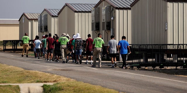 In this July 9, 2019, file photo, staff escort immigrants to class at the U.S. government's newest holding center for migrant children in Carrizo Springs, Texas. A federal judge on Friday blocked the Trump administration from ending the so-called Flores Settlement, a longstanding settlement governing detention conditions for immigrant children, including how long they can be held by the government.  (AP Photo/Eric Gay, File)