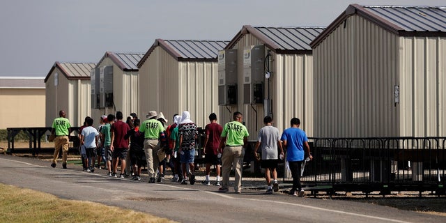 In this July 9, 2019, file photo, staff escort immigrants to class at the U.S. government's newest holding center for migrant children in Carrizo Springs, Texas. A federal judge on Friday blocked the Trump administration from ending the so-called Flores Settlement, a longstanding settlement governing detention conditions for immigrant children, including how long they can be held by the government.  (AP Photo/Eric Gay, File)