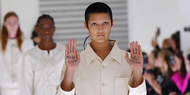 Ayesha Tan-Jones put their own twist on their assigned outfit — a utilitarian, white jumpsuit — by holding up their hands with the message “mental health is not fashion” written on their palms during the recent Gucci show.