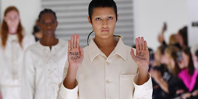 Ayesha Tan-Jones put their own twist on their assigned outfit — a utilitarian, white jumpsuit — by holding up their hands with the message “mental health is not fashion” written on their palms during the recent Gucci show.