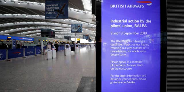 A screen at Heathrow Airport's Terminal 5 displays a message from British Airways, which writes that it is "deeply sorry" about the cancelations.