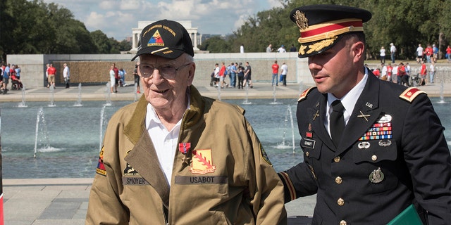 U.S. Army Major Peter Semanoff guides Clarence Smoyer back to his seat after awarding him the Bronze Star at the National WWII Memorial in Washington, D.C. (DoD photo by U.S. Navy Petty Officer 2nd Class James K. Lee)