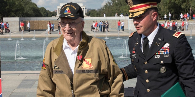 U.S. Army Major Peter Semanoff guides Clarence Smoyer back to his seat after awarding him the Bronze Star at the National WWII Memorial in Washington, D.C. (DoD photo by U.S. Navy Petty Officer 2nd Class James K. Lee)