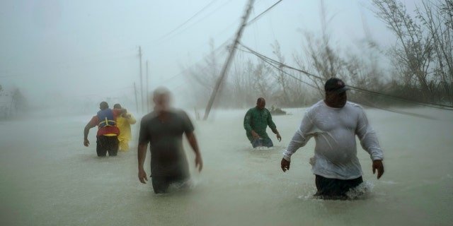 Volunteers walk under the wind and rain from Hurricane Dorian through a flooded road as they work to rescue families near the Causarina bridge in Freeport, Grand Bahama, Bahamas, Tuesday,