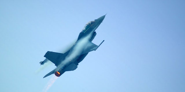 An F16 plane rising into the sky, visible burner.