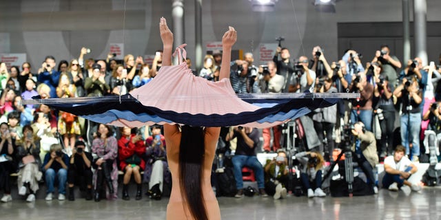 A model on the runway during the Issey Miyake Ready to Wear Spring/Summer 2020 fashion show as part of Paris Fashion Week. The dress was dropped on the model using a pulley system.