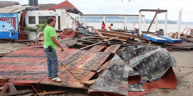 Residents stand near debris from a restaurant damaged by rain storm caused by Tropical Storm Lorena at a beach in Manzanillo, in Colima state, Mexico.
