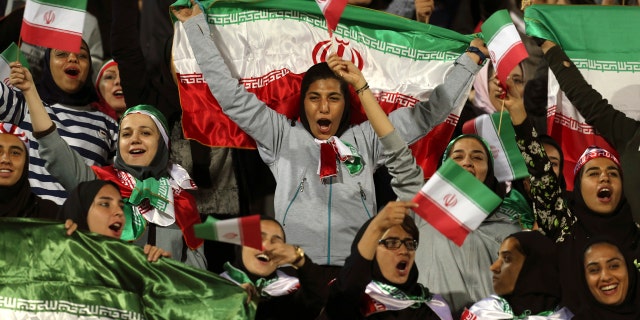 In this Oct. 16, 2018 file photo, Iranian women cheer as they wave their country's flag after authorities in a rare move allowed a select group of women into Azadi stadium to watch a friendly soccer match between Iran and Bolivia, in Tehran, Iran.