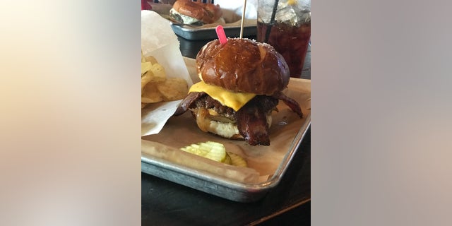 The "Labor Inducer" burger contains an angus beef patty, honey-cured bacon, peach caramelized onions, spicy mustard and Cajun remoulade on a pretzel bun.