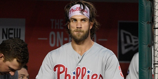 Philadelphia Phillies' Bryce Harper, center, stands in the dugout before a baseball game against the Washington Nationals, Monday, Sept. 23, 2019, in Washington. 