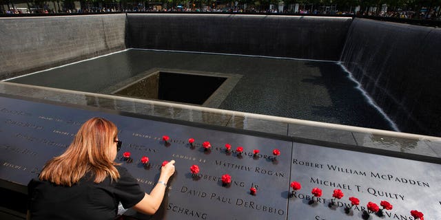 Norma Molina, of San Antonio, Texas, leaves flowers by the names of firefighters from Engine 33 at the September 11 Memorial, Monday, Sept. 9, 2019, in New York. Her boyfriend Robert Edward Evans, a member of Engine 33, was killed in the north tower of the World Trade Center on Sept. 11, 2001. (AP Photo/Mark Lennihan)