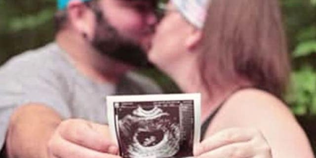 Elisha and Tyler Hessel, showing an ultrasound of their unborn daughter.