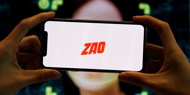 The logo of the Chinese app ZAO, which allows users to swap their faces with celebrities and anyone else, is seen on a mobile phone screen in front of an advertisement of the app, in this illustration picture taken September 2, 2019.