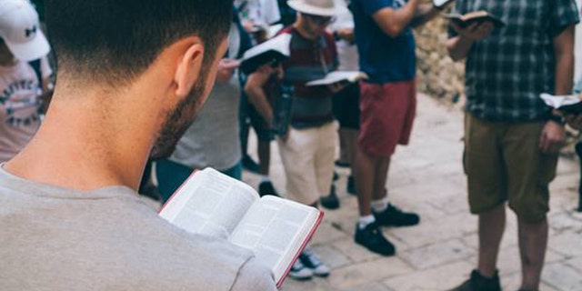 Students read their Bibles at a holy site in Israel with the Passages Israel trip.