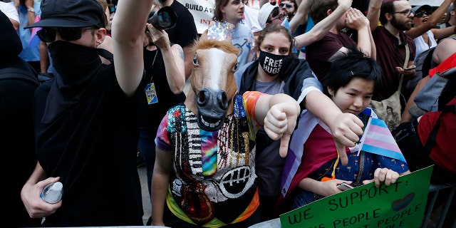 Counterprotesters, including one wearing a horse mask, line the route of the Straight Pride Parade in Boston, Saturday, Aug. 31, 2019. (AP Photo/Michael Dwyer)